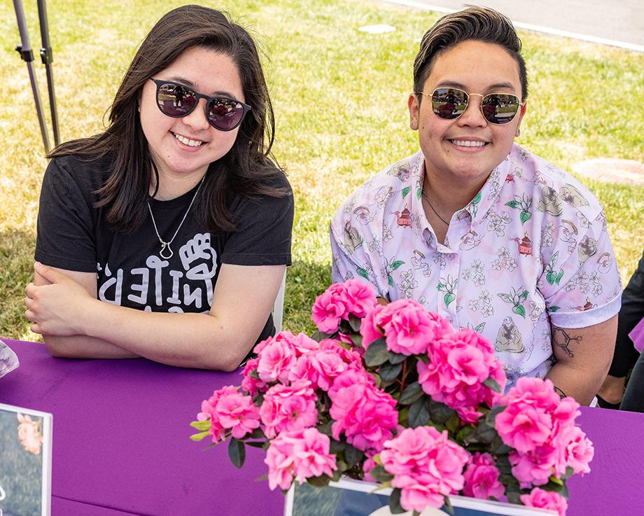 Two 澳门正规博彩十大排行平台 employees celebrate AANHPI Heritage Month at a table with pink flowers